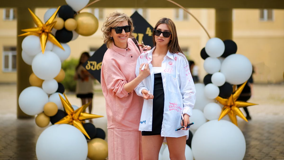 A mother and daughter enjoying a celebration, surrounded by decorative balloons and stars outdoors.